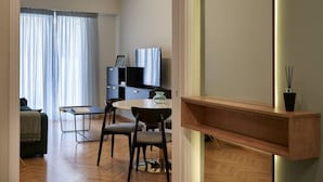 A modern living room with a dining area, a TV, and a wooden shelf. - Little Gem: Modern Urban Retreat (Athina)