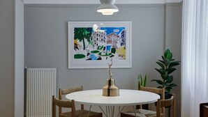 Comedor con una mesa redonda, cuatro sillas, una obra de arte enmarcada, una planta y un radiador.