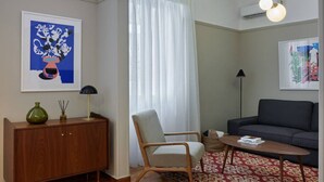 Una sala de estar con un aparador de madera, una silla, un sofá, una mesa de centro y un tapete estampado.