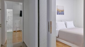 Et hotelværelse med en seng, et billede på væggen og en dør til et andet rum.