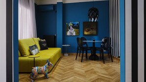 A room with a yellow sofa, a small round table, and two chairs. There is a colorful dog sculpture on the floor. - Art Deco Apt in Kolonaki (Athina)