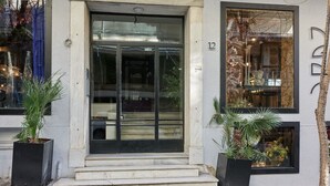 A building with a glass door entrance, steps leading up to it, and two potted plants on either side. - Art Deco Apt in Kolonaki (Athina)