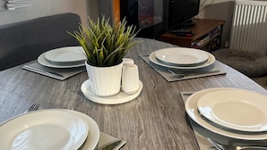 A dining table set with plates, cutlery, and a potted plant. - 3 bed Stunning Caravan Situated nr Whitstable (Whitstable)