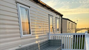 A covered outdoor area with a bench and a white railing. - 3 bed Stunning Caravan Situated nr Whitstable (Whitstable)