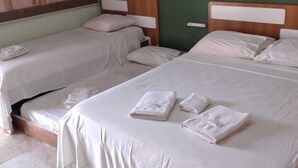 A hotel room with two single beds, each with a wooden headboard and white bedding. There are towels neatly folded on each bed. - Clube Praiano (Cabo Frio)
