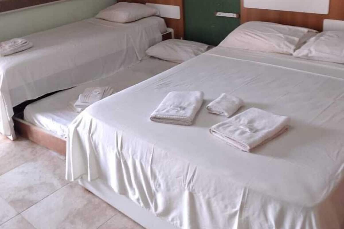 Ein Hotelzimmer mit zwei Einzelbetten, jeweils mit Holz Kopfteil und weißer Bettwäsche. Auf jedem Bett liegen ordentlich gefaltete Handtücher.