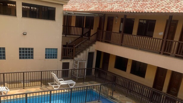 A multi-story building with a swimming pool, balconies, and a tiled roof. - Clube Praiano (Cabo Frio)