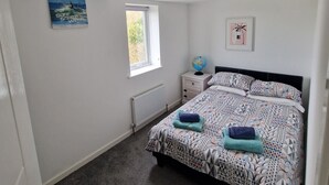 A bedroom with a bed, a nightstand, a globe, and a window. - Charming 3-bed House in Newquay (Newquay)