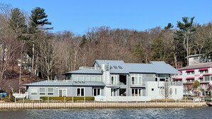 A waterfront property with a large house featuring multiple levels, a dock, and a view of the water. - Stunning 3BR Condo w/6 Decks & a Boat Dock (Saugatuck)