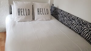 A bed with two white pillows that read "HELLO" and a zebra-patterned headboard.