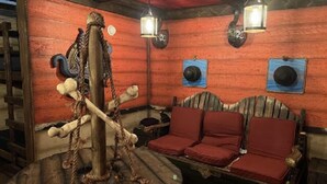 A rustic room with a wooden bench, a rope sculpture, and two wall-mounted lanterns. - Pirate Ship - Deluxe Cabin #3 on map (Bayfield)
