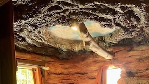 Una habitación con cama, paredes de piedra y ventana con cortinas.