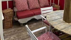 Une cabane chaleureuse avec un banc en bois, une petite table et une fenêtre avec un rideau.