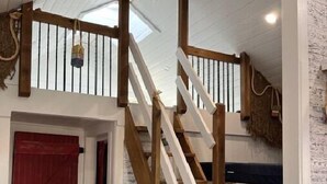 Un escalier en bois avec une rampe blanche menant à une mezzanine.
