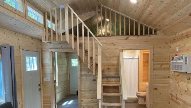 Un interior de madera con una escalera, un sofá y una mesa.