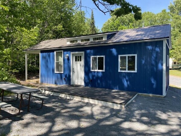 A small, single-story building with a blue exterior, a front door, and two windows.