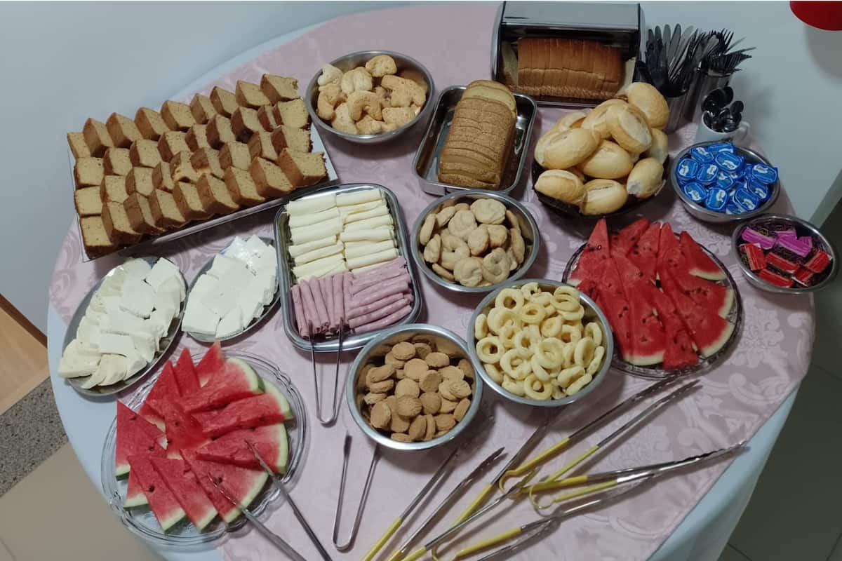 A table with various food items including bread, cheese, ham, crackers, and watermelon slices.