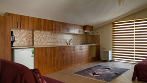 Eine Küche mit Holzausstattung, einer gefliesten Spritzschutzwand, einem Kühlschrank und einem Fenster mit Jalousien.