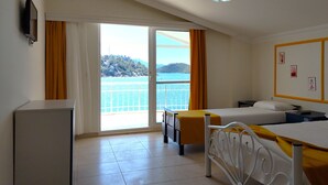 Ein Hotelzimmer mit zwei Betten, einem Schreibtisch, einem Stuhl und Meerblick.