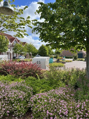 Un quartiere residenziale con file di case, un campanile e un giardino curato con fiori rosa.