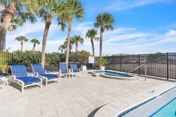 A poolside area with lounge chairs, a small pool, and palm trees.
