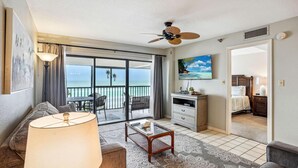 A hotel room with a balcony, a ceiling fan, a TV, a bed, and a dining area with a table and chairs. - Arie Dam 202 (Madeira Beach)