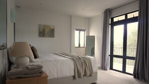 A bedroom with a bed, a bedside table, a mirror, and a window with curtains. - Tuscan Villa with a view. (Havelock North)