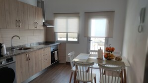 A modern kitchen with wooden cabinets, a granite countertop, and a dining area with white chairs and a table. - Carmen´s House (Arico Viejo)