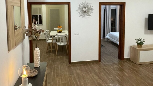 A modern hotel room with a wooden floor, a dining area with a table and chairs, a bed, and a TV mounted on the wall. - Carmen´s House (Arico Viejo)