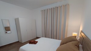 A hotel room with a bed, a wardrobe, a mirror, and a window with curtains. - Carmen´s House (Arico Viejo)