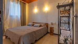 Une chambre à coucher avec un lit, des rideaux, des appliques murales, un porte-serviettes en métal et une tête de lit en bois.