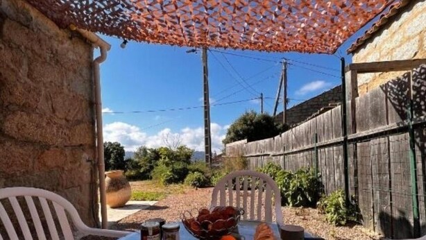 Une terrasse extérieure avec une table ronde, deux chaises blanches et un parasol décoratif.