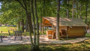 Ein rustikaler Campingplatz mit einem Holzzelt, Picknicktischen und Bänken.