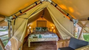 Ein Zelt mit Bett, Stuhl und Holzboden.