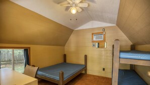 Ein Schlafsaalzimmer mit Etagenbetten, einem Deckenventilator, einem Fenster und einem Tisch.