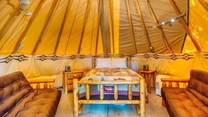 A tent with a bed, two chairs, and a small table.
