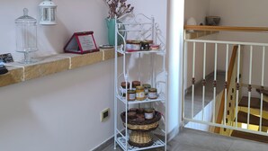 A corner of a room with a white shelf holding jars, a white lantern, and a vase with dried plants. - Avola Opera House (Avola)