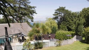 A backyard with a stone pathway leading to a lawn, surrounded by trees and a pool. - Bourne Hall Country Hotel (Shanklin)