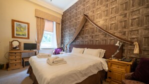 A bedroom with a large bed, a wooden desk, a chair, a nightstand, and a lamp. - Bourne Hall Country Hotel (Shanklin)