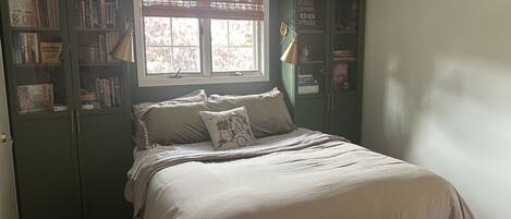 A bedroom with a bed, a window, and built-in bookcases.