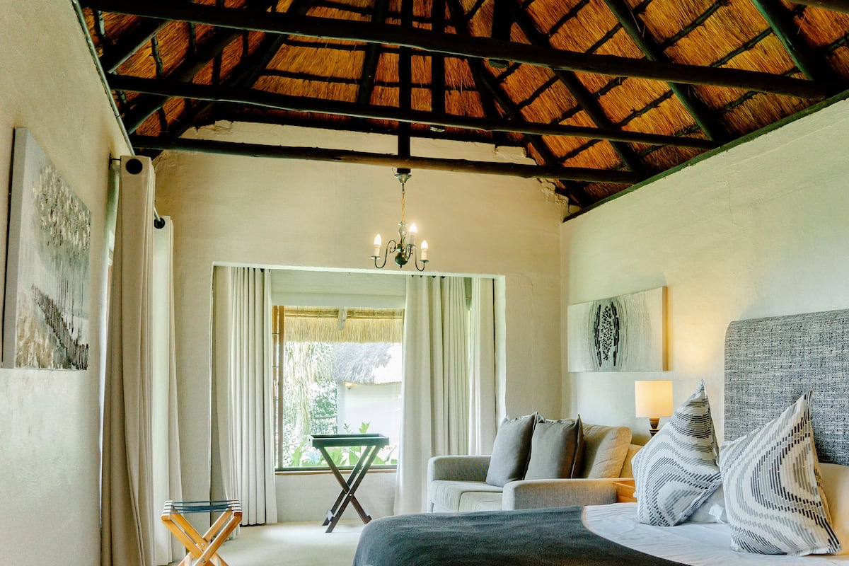 Un dormitorio con cama, sofá, mesa y candelabro.