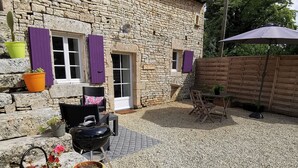 A stone building with a gravel patio, outdoor seating, and potted plants. - Les Gîtes de La Roche Élie-chez Théophile (ROM)
