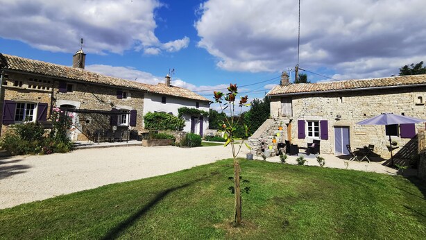 A courtyard with stone buildings, a small garden, and a clear sky. - Les Gîtes de La Roche Élie-chez Théophile (ROM)