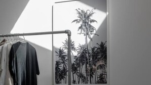 A room with a clothing rack and a framed picture of palm trees. - PYLA: Nice creative studio 200 m from the beach (La Teste-de-Buch)