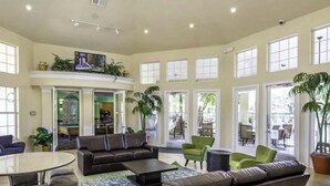 A spacious lobby with a high ceiling, large windows, and a variety of seating options including sofas and chairs.