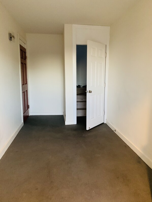 A hallway with carpeted floors, white walls, and a wooden door.