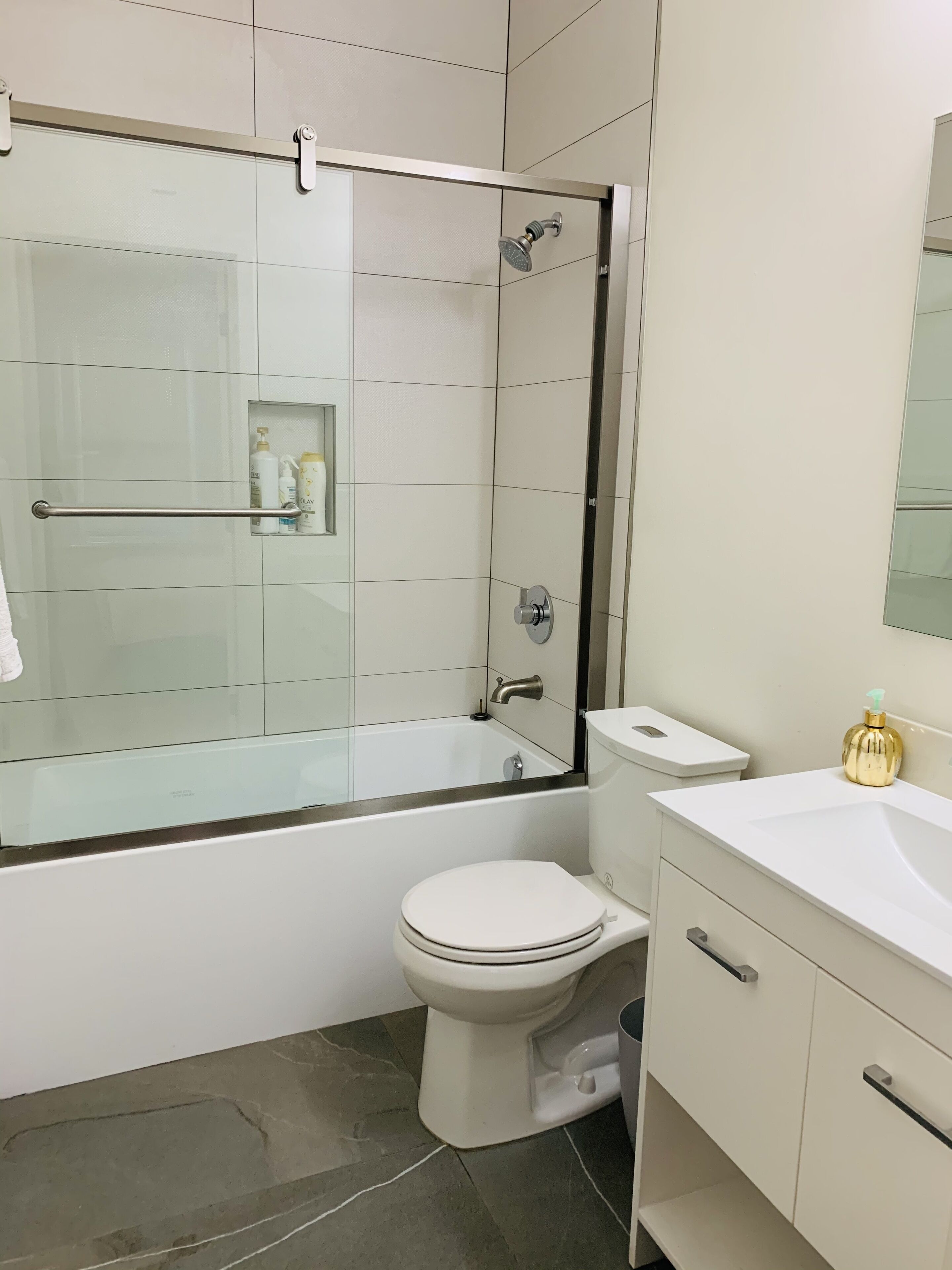 Une salle de bain moderne dotée d’une douche à parois de verre, de toilettes et d’un meuble-lavabo avec un évier.