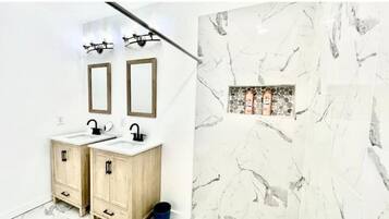 Ein Badezimmer mit zwei Waschbecken, Holzschränken und einer Marmor-Spritzschutzwand.