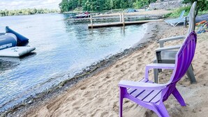 Ein Strand mit einer Anlegestelle, Schlauchbooten und einem violetten Stuhl.