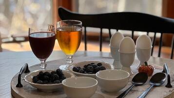 A breakfast setting with eggs, blueberries, and two glasses of beverages on a wooden table.